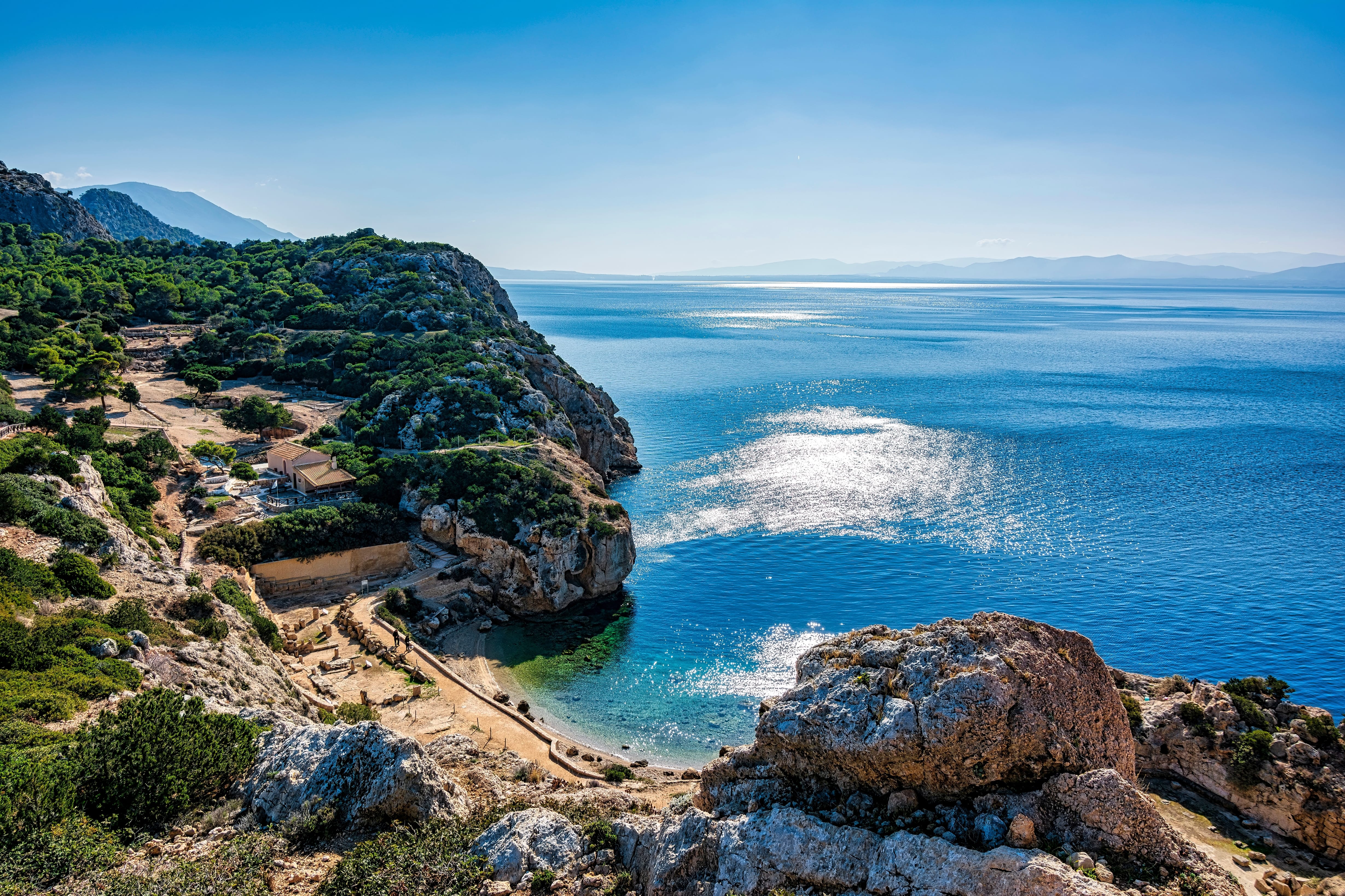 a rocky beach with a body of water in the background