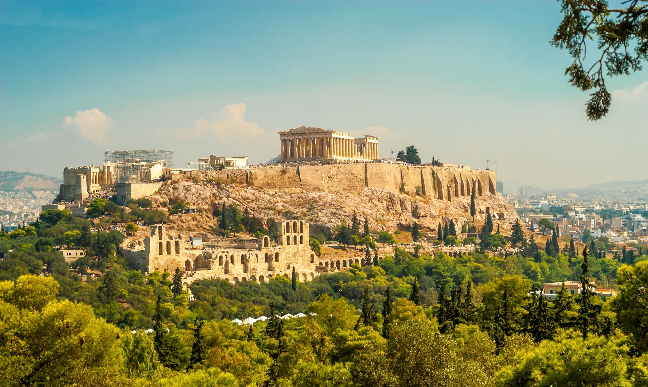 a large stone building on a hill with Acropolis of Athens in the background