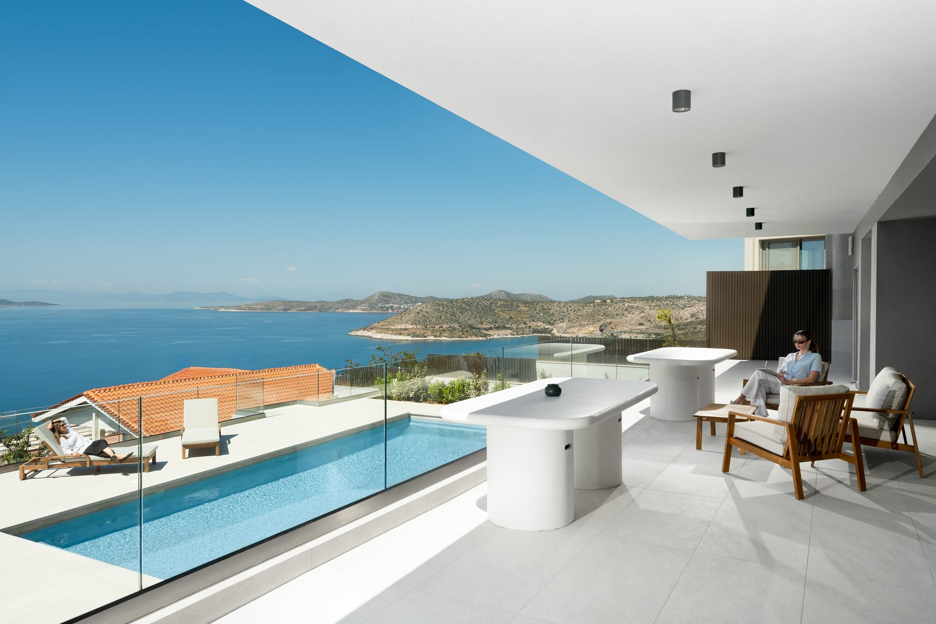a white patio with a pool overlooking the ocean