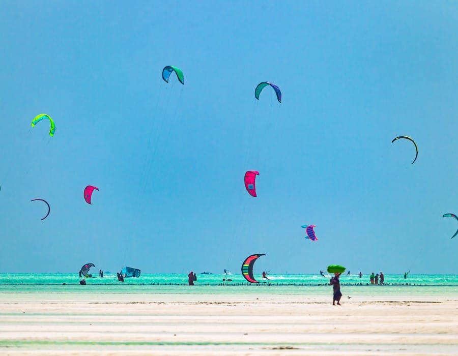 a group of people flying kites at the beach