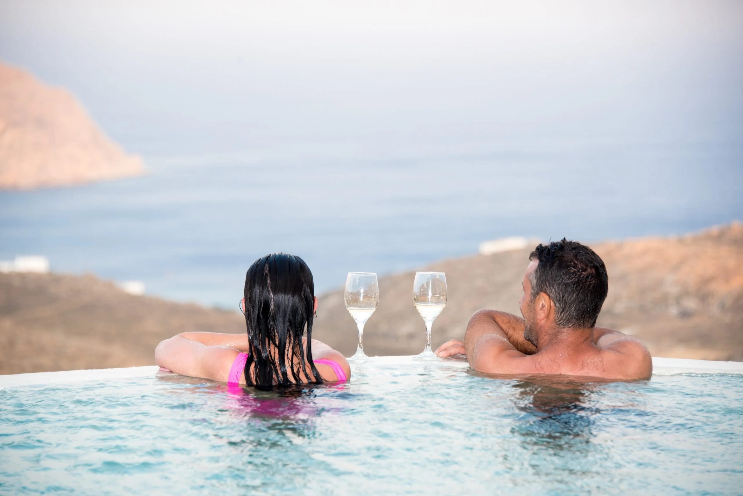 a man and a woman in a pool with glasses and a surfboard