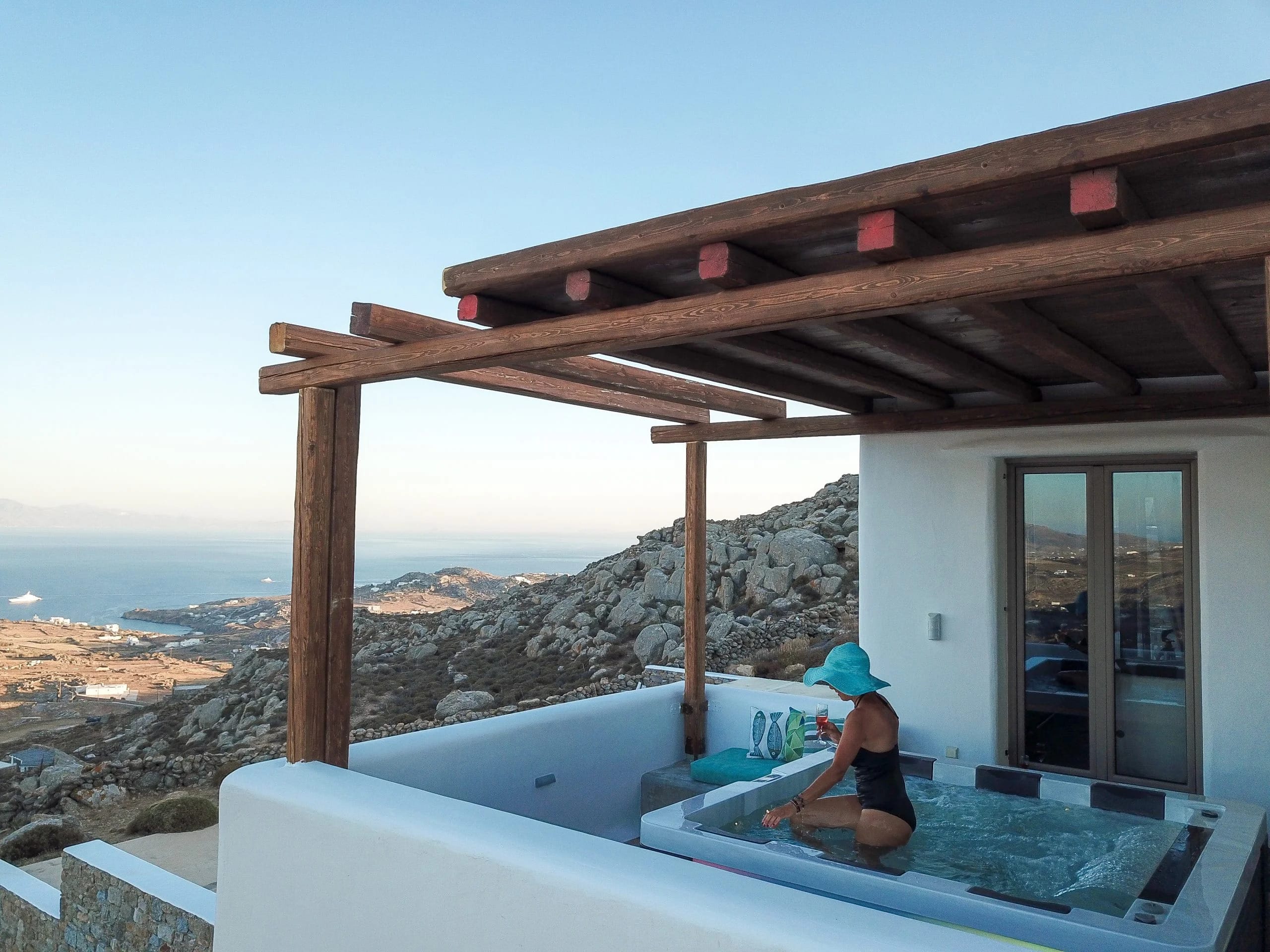 a person sitting on a deck of a house with a view of the ocean and mountains in the