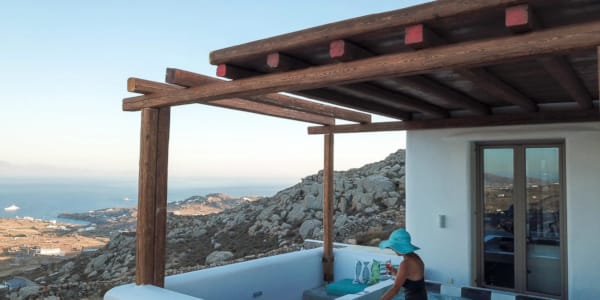 a person sitting on a deck of a house with a view of the ocean and mountains in the