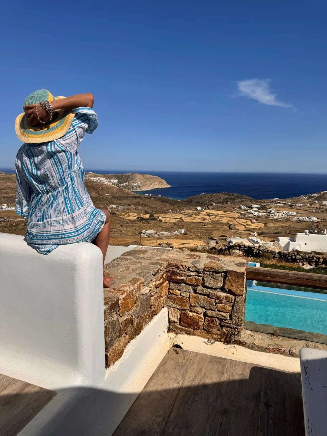 a person sitting on a ledge overlooking a city and the ocean