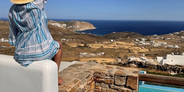 a person sitting on a ledge overlooking a city and the ocean