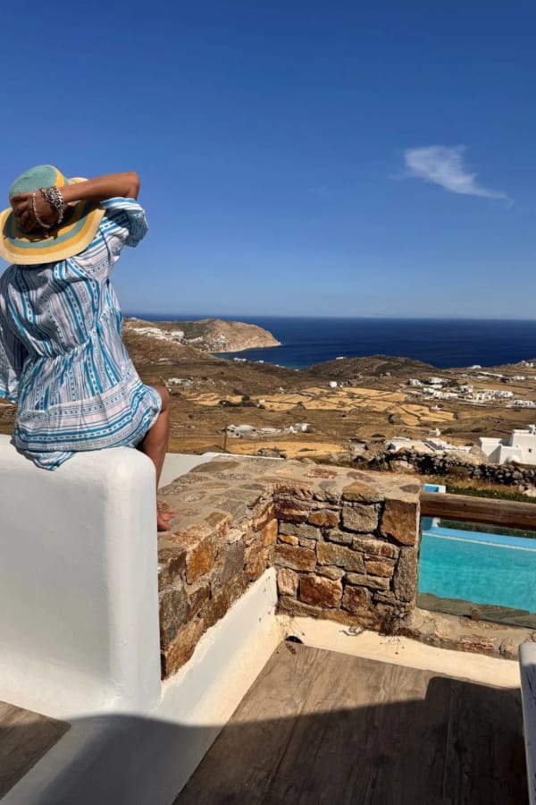 a person sitting on a ledge overlooking a city and the ocean