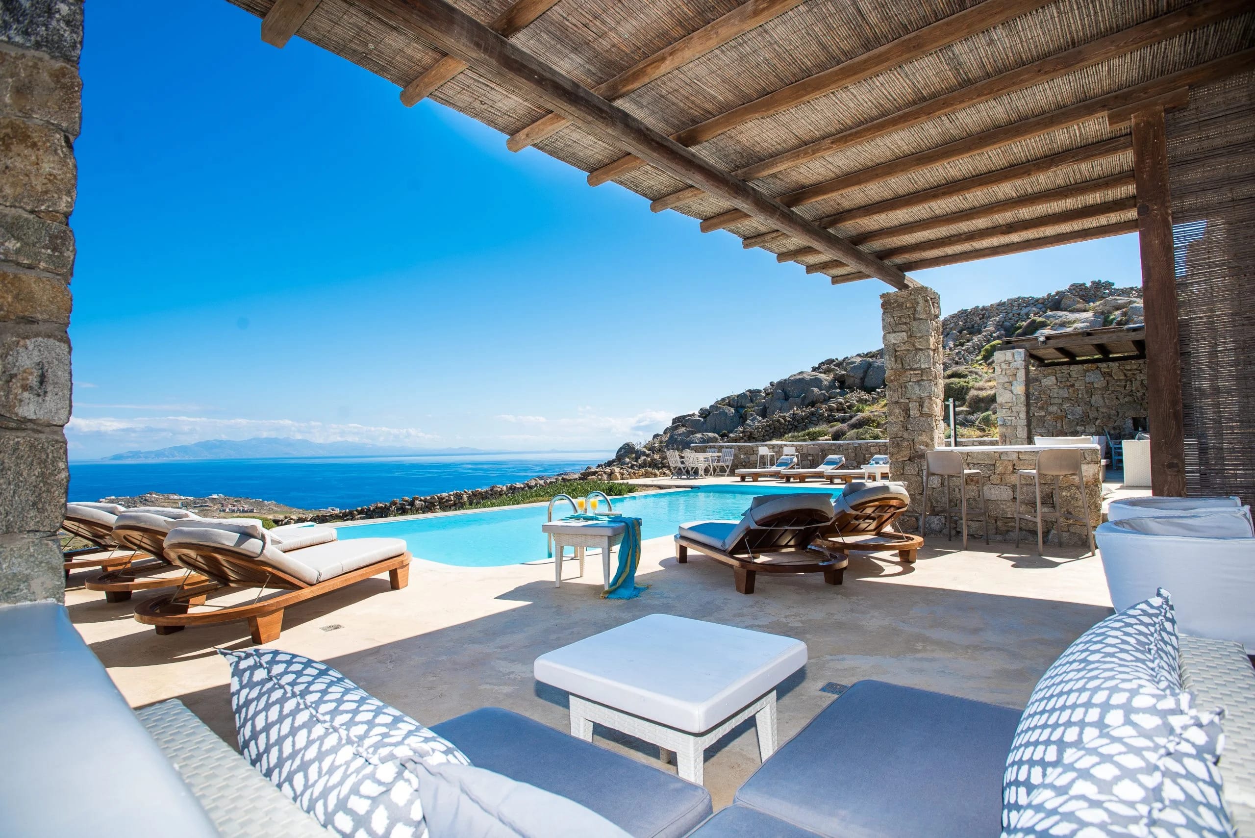 a pool with lounge chairs and a view of the ocean