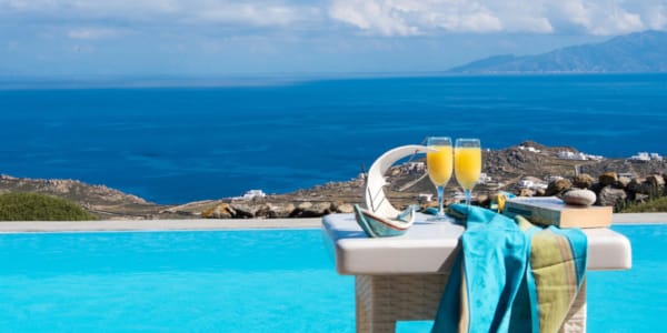 a table with glasses of wine on it by a body of water