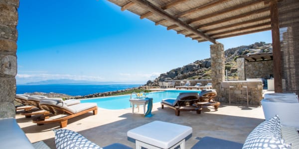 a pool with lounge chairs and a view of the ocean