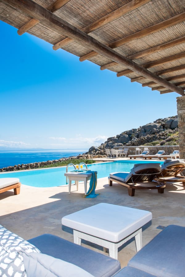 a pool with lounge chairs and a view of the ocean