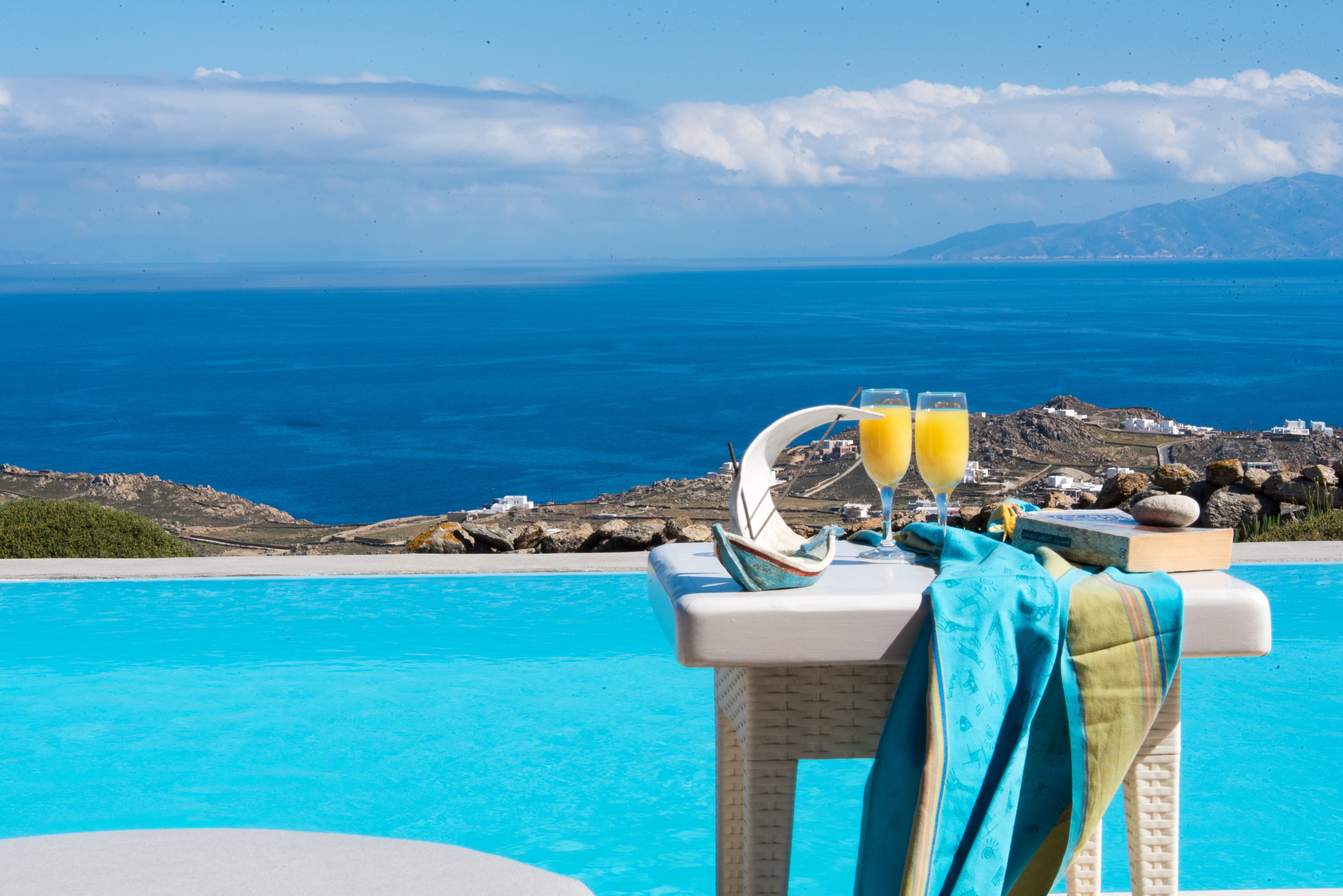 a table with glasses and a couple of glasses on it by a body of water