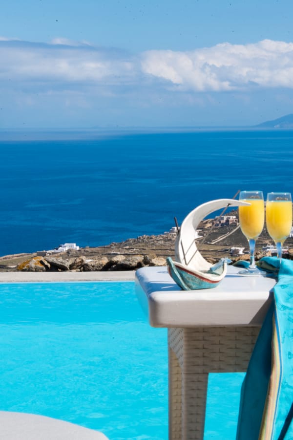 a table with glasses and a couple of glasses on it by a body of water