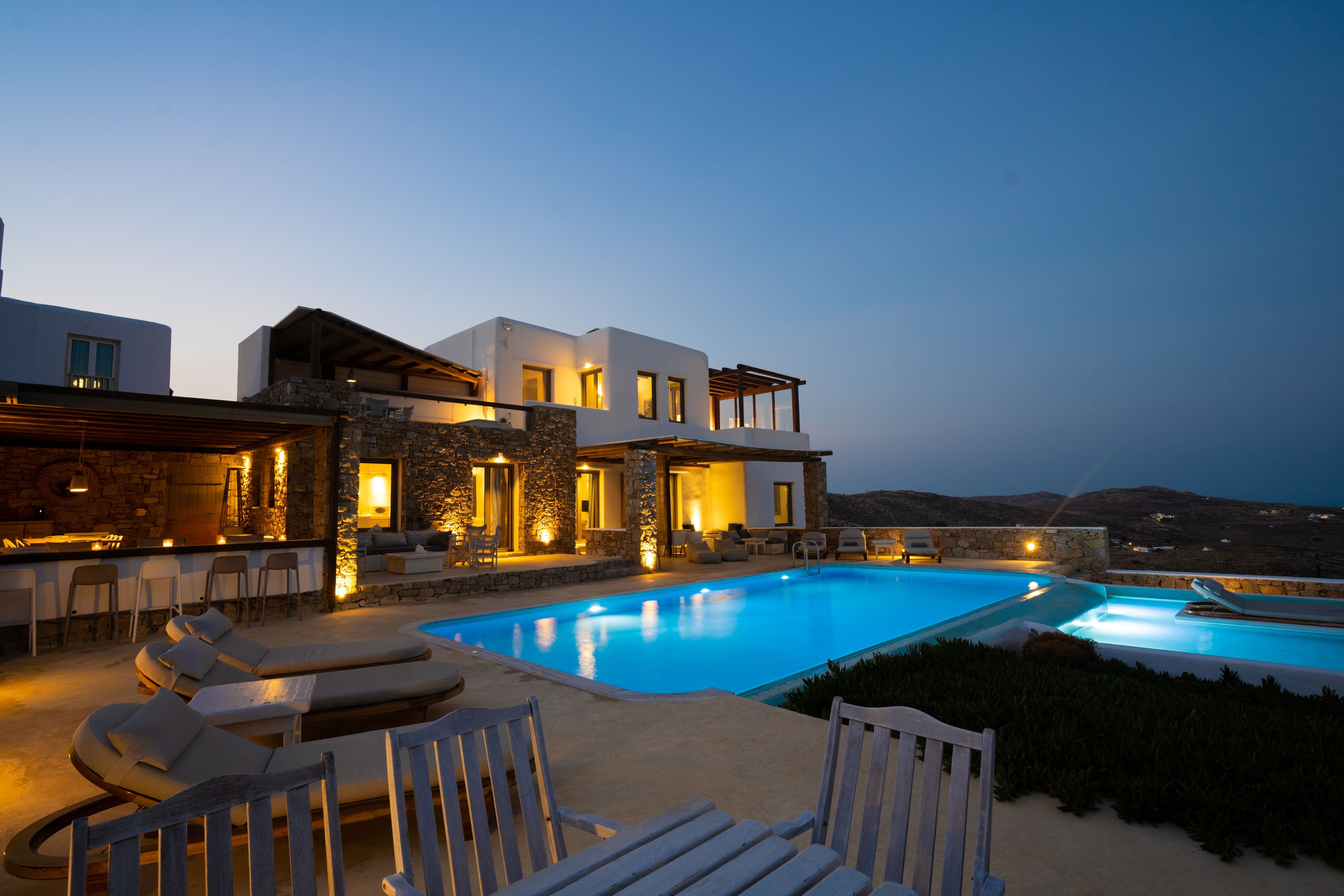 a house with a pool and a deck with chairs and a view of the ocean