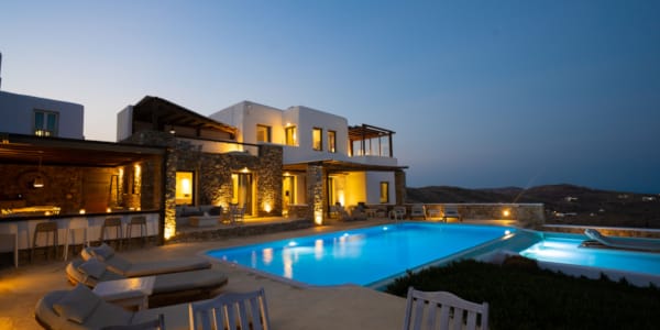 a house with a pool and a deck with chairs and a view of the ocean