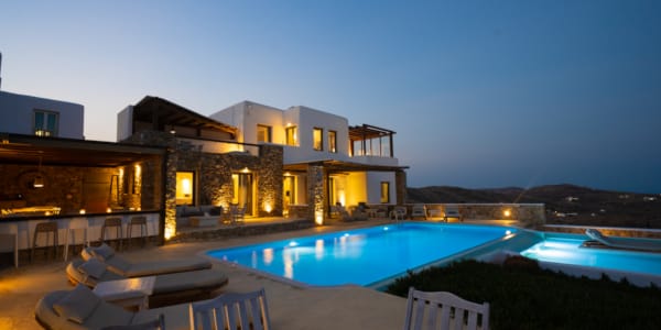 a house with a pool and a deck with chairs and a view of the ocean