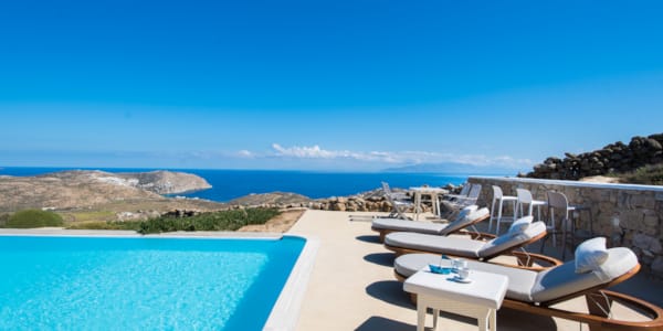 a pool and lounge chairs by a beach