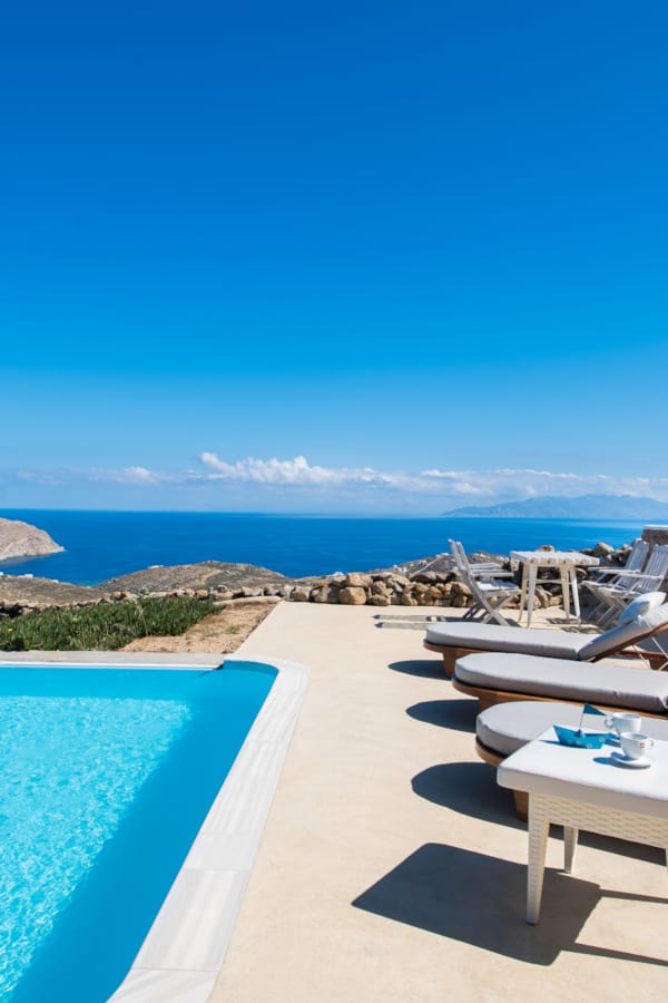 a pool and lounge chairs by a beach