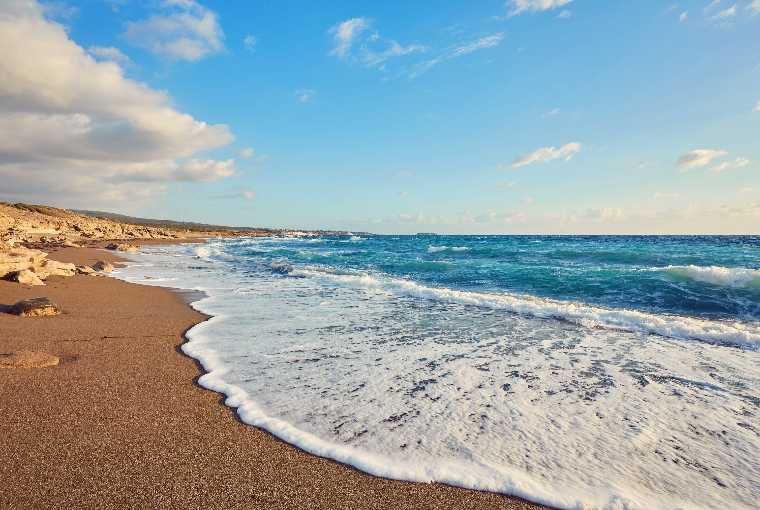 a sandy beach with waves crashing on it