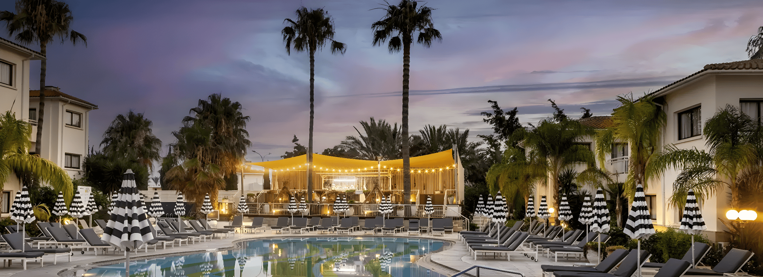 a pool with palm trees and a building in the background