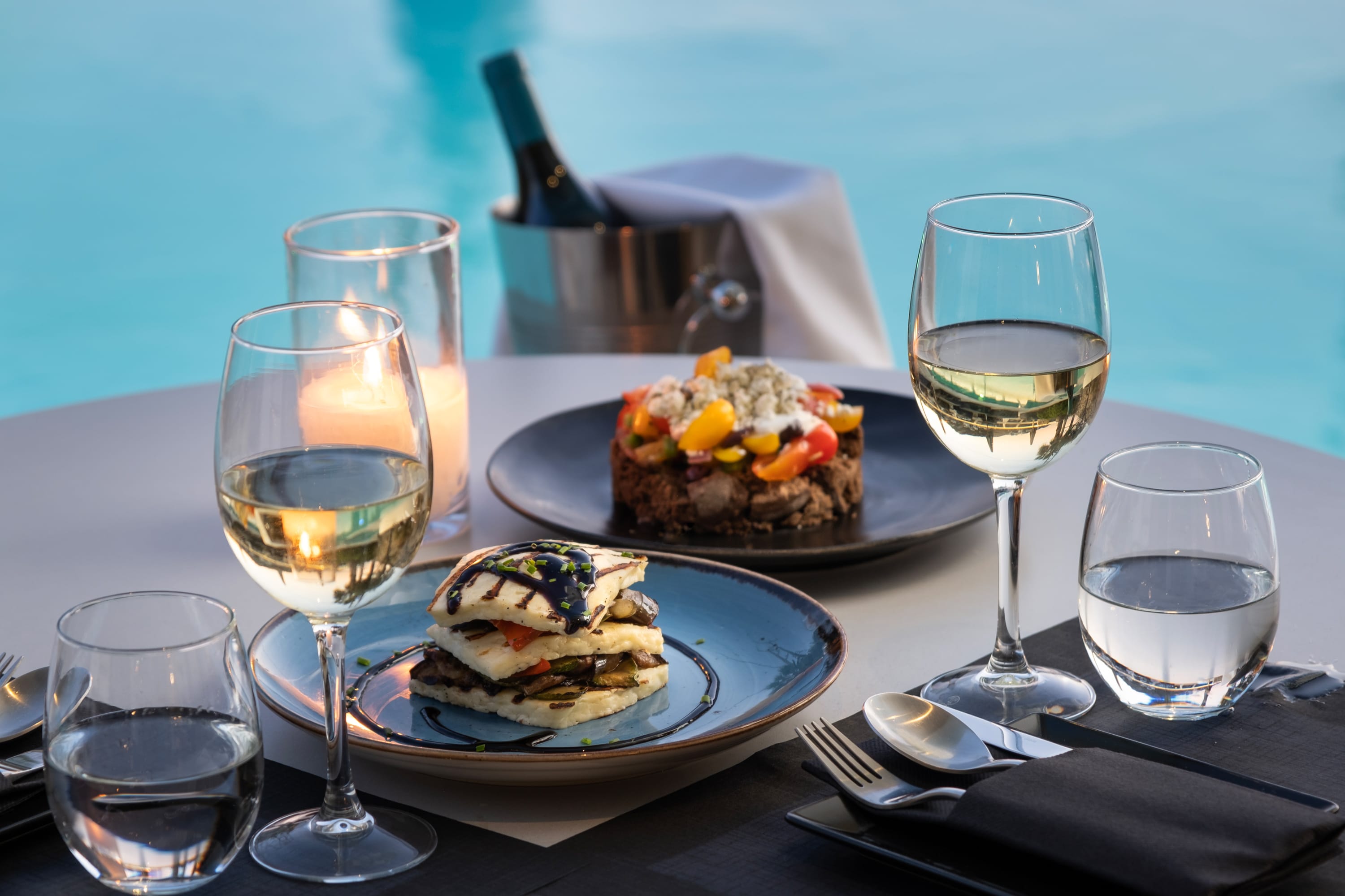 a table with plates of food and wine glasses