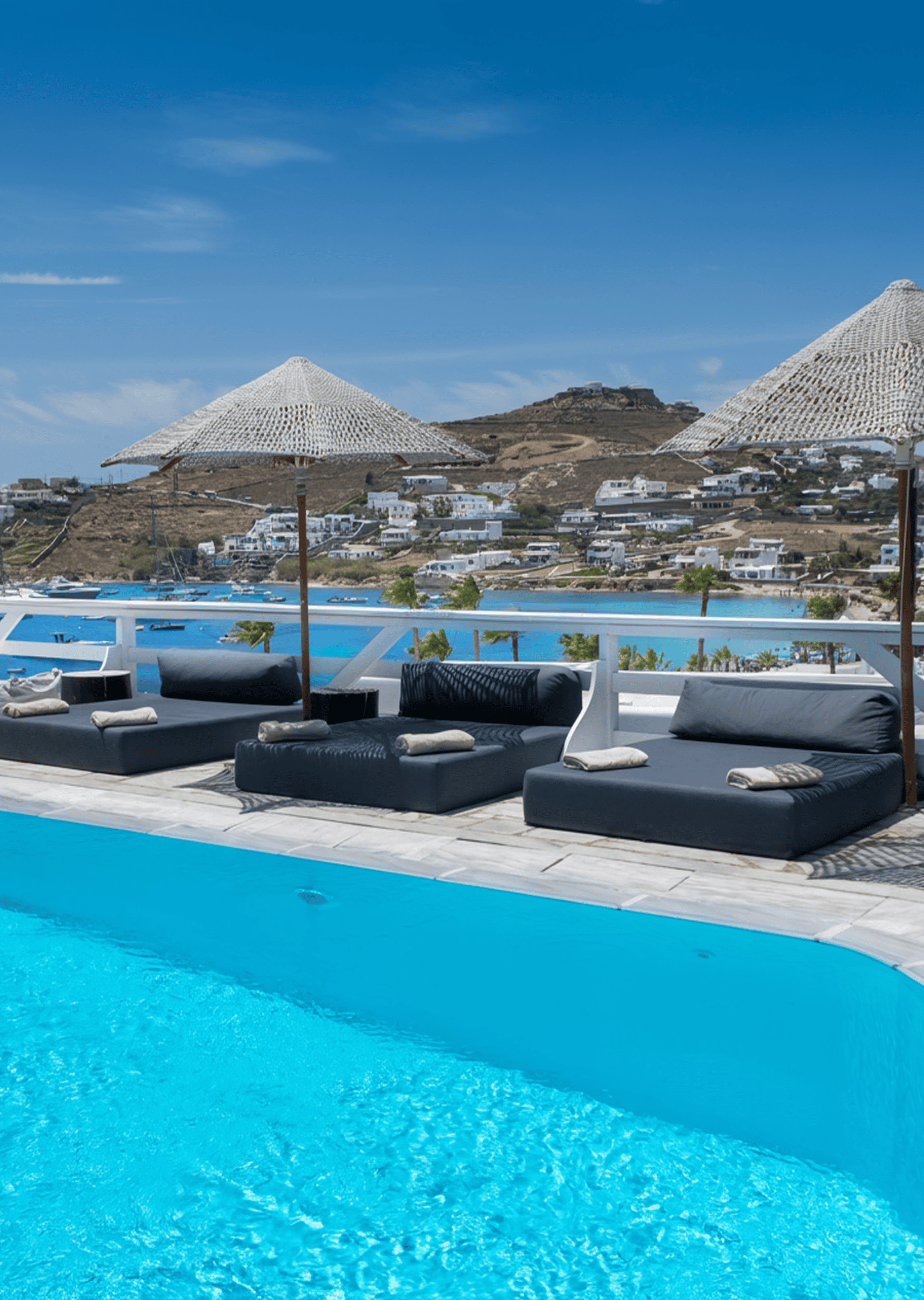 a pool with a lounge chair and umbrella by a beach