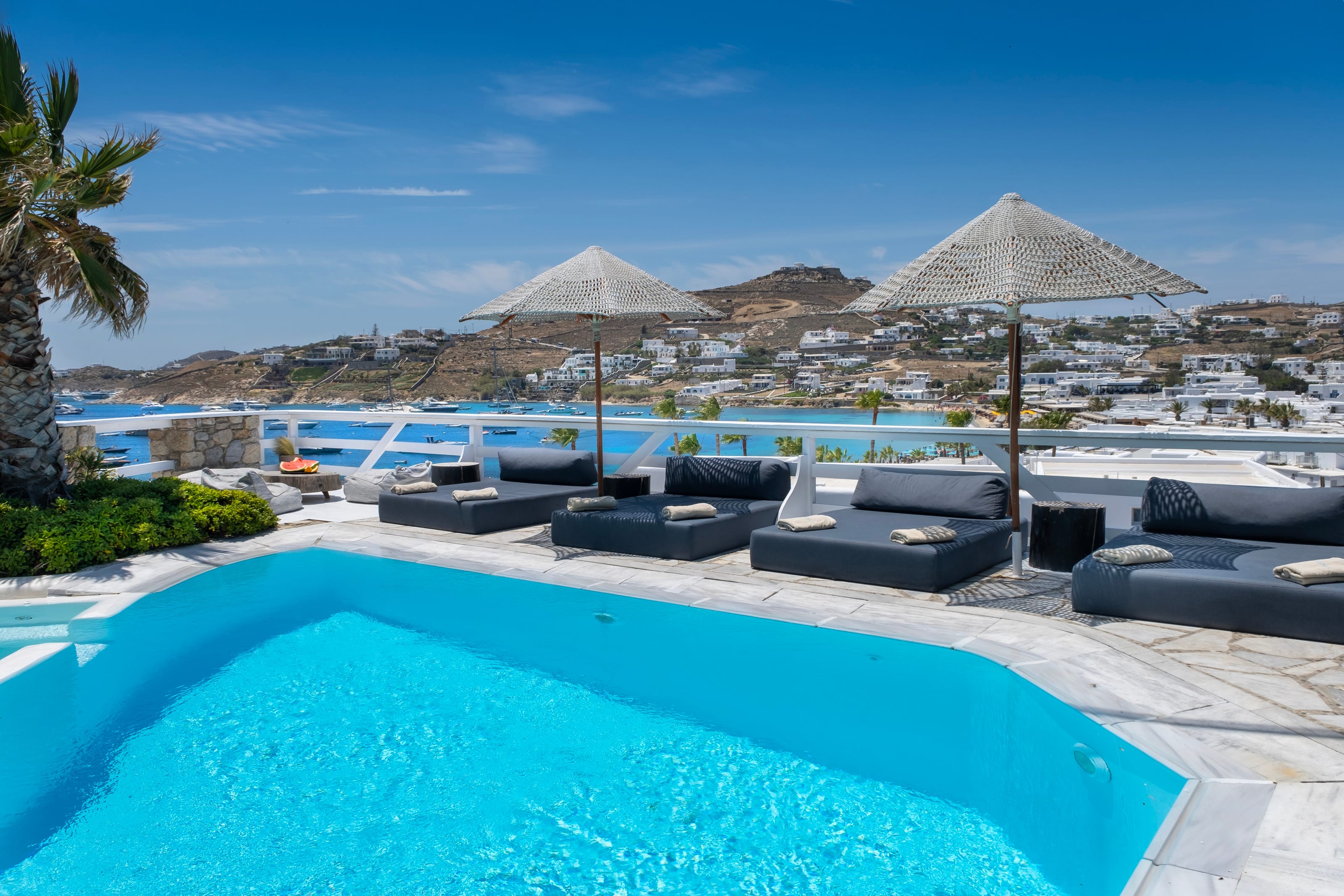 a pool with lounge chairs and umbrellas by a beach