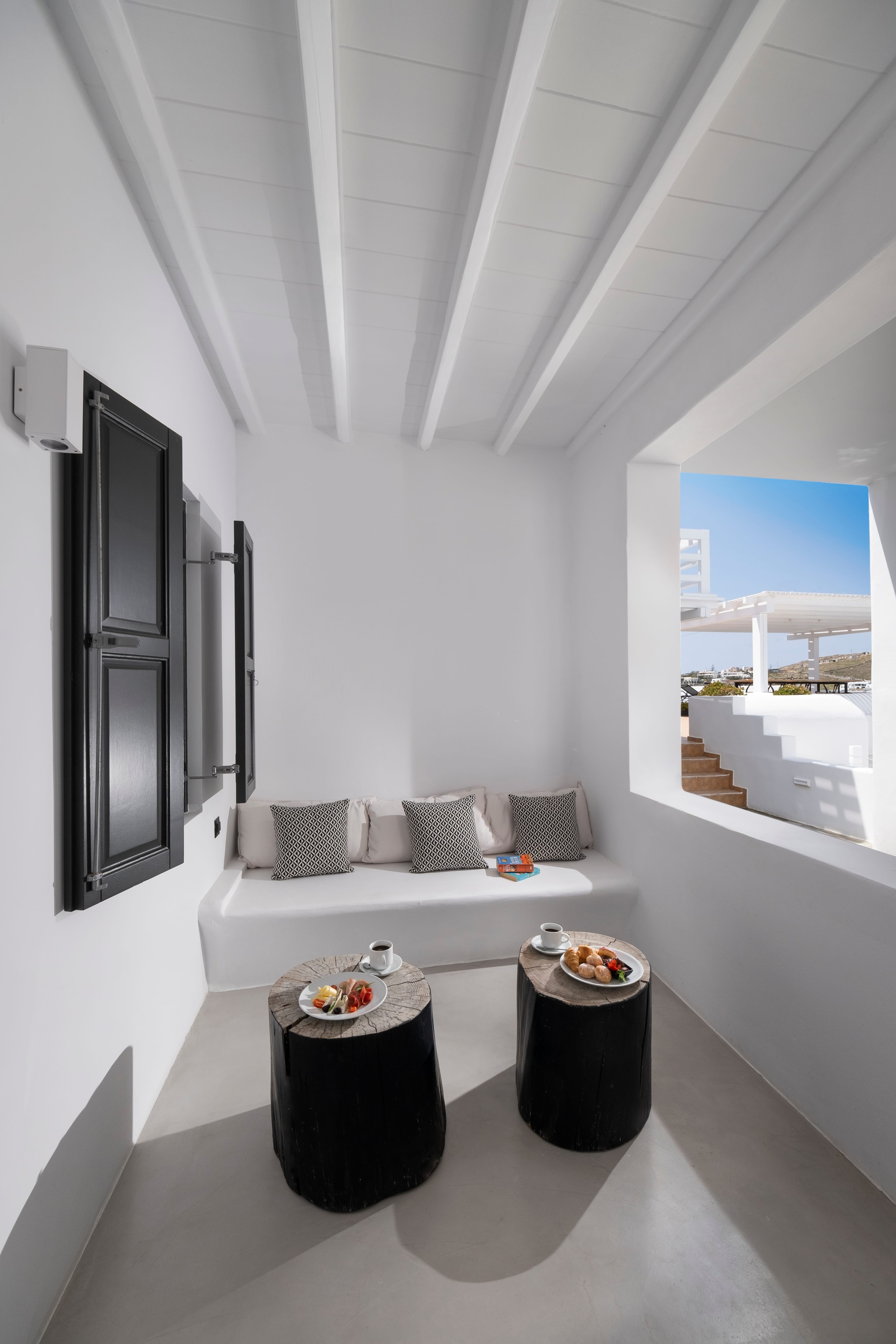 a white room with a white couch and a black trash can