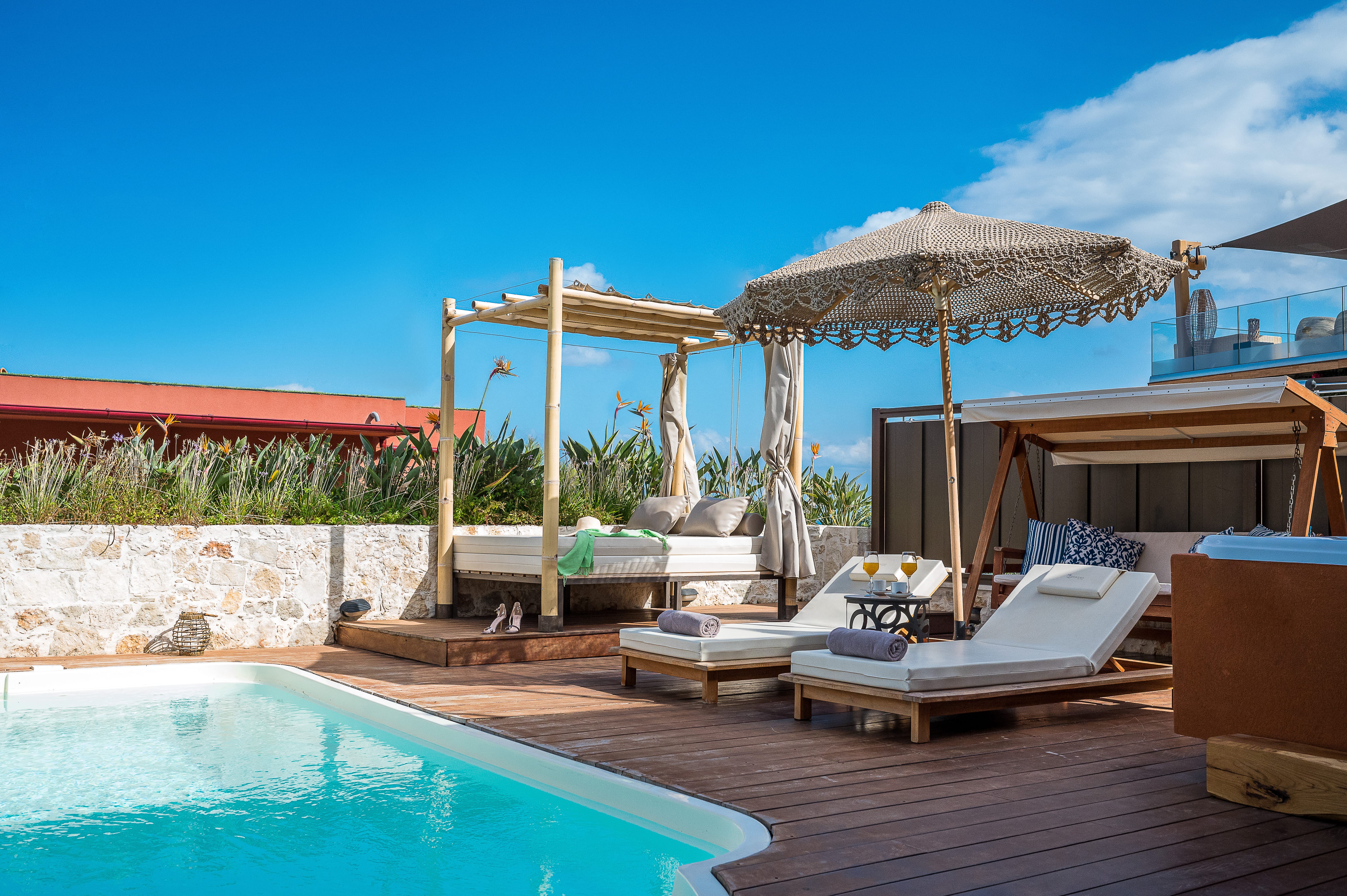 a pool with lounge chairs and umbrellas by a building