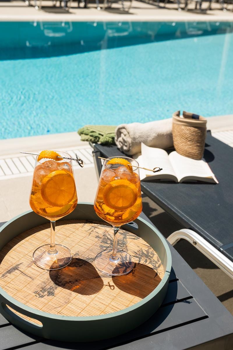 two glasses of beer on a table by a pool