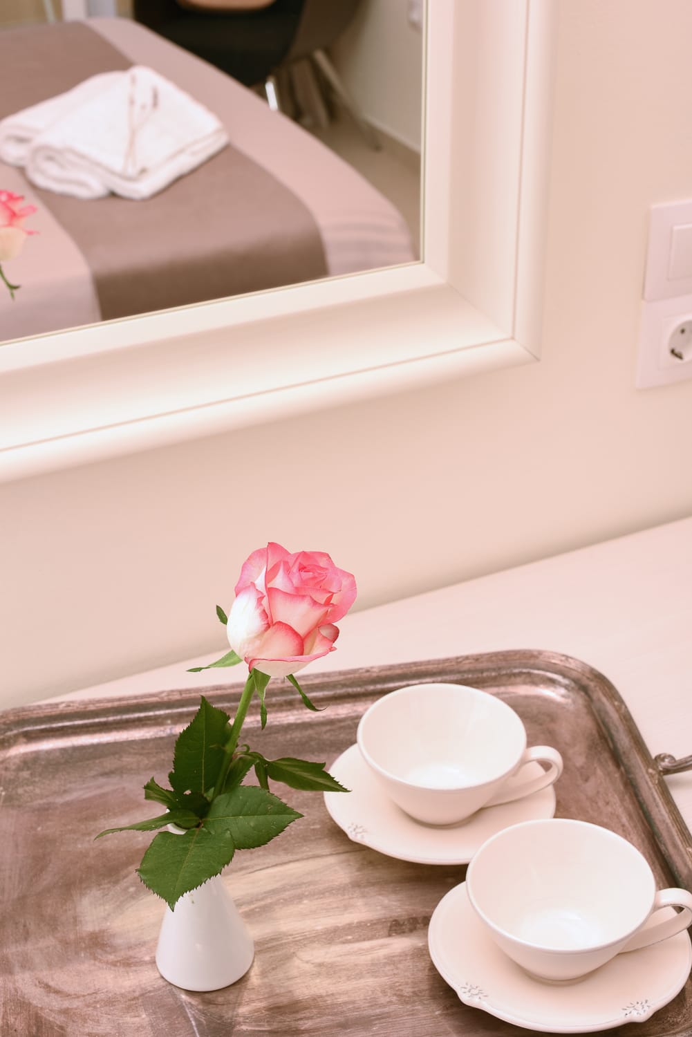 a pink rose in a white vase