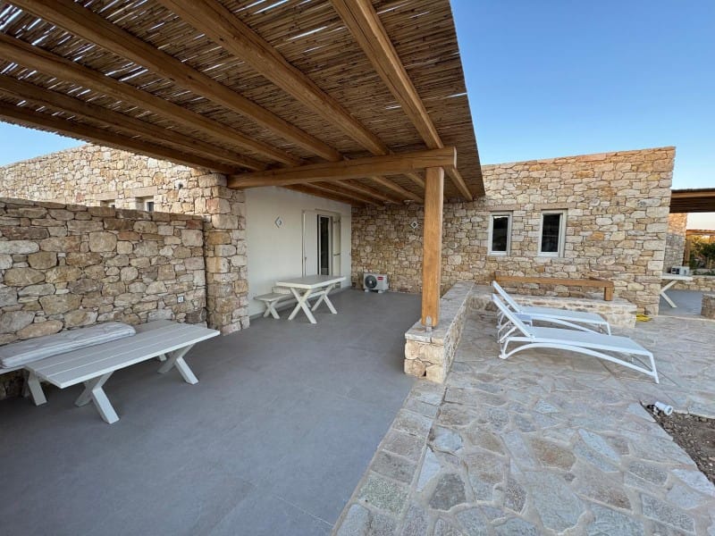 a stone patio with a bench and a covered patio