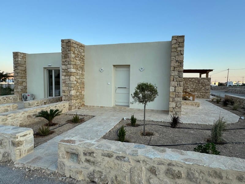 a building with a stone wall and a tree in front