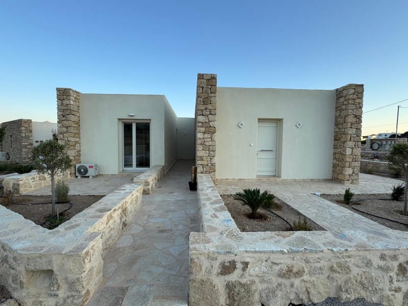 a stone courtyard with a stone wall and a stone building with a stone wall and a blue sky