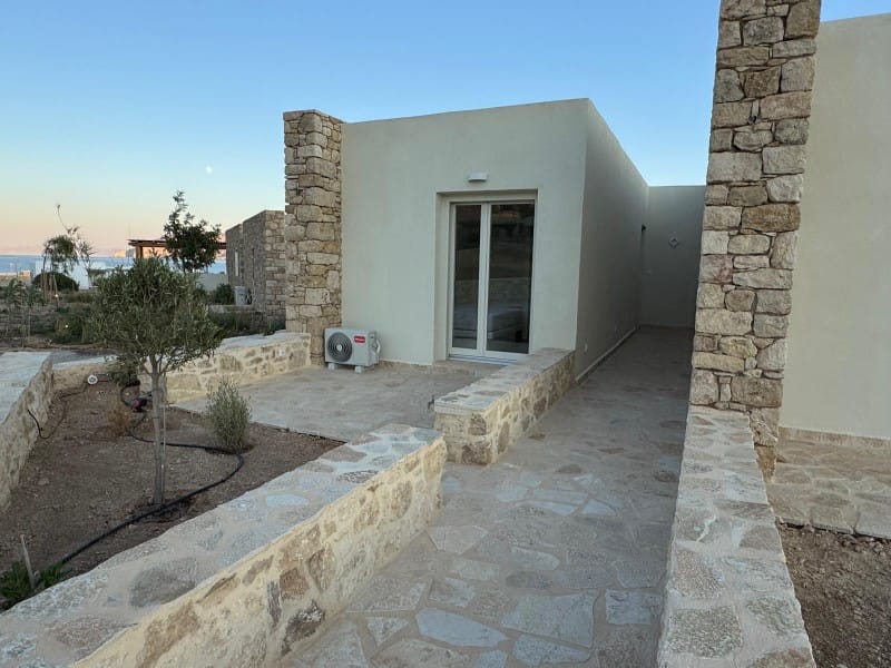 a stone patio with a door and a stone wall with a tree and a building in the background