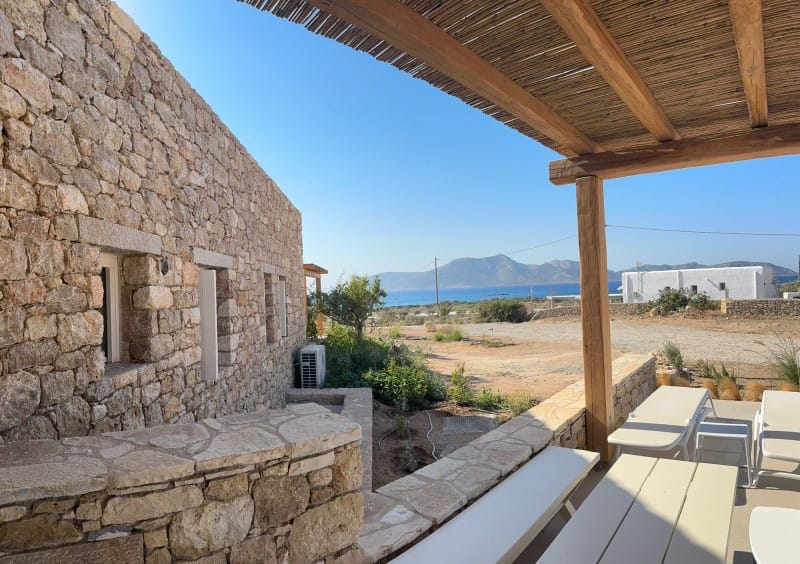 a patio with a stone wall and a stone building with a view of the ocean and mountains in