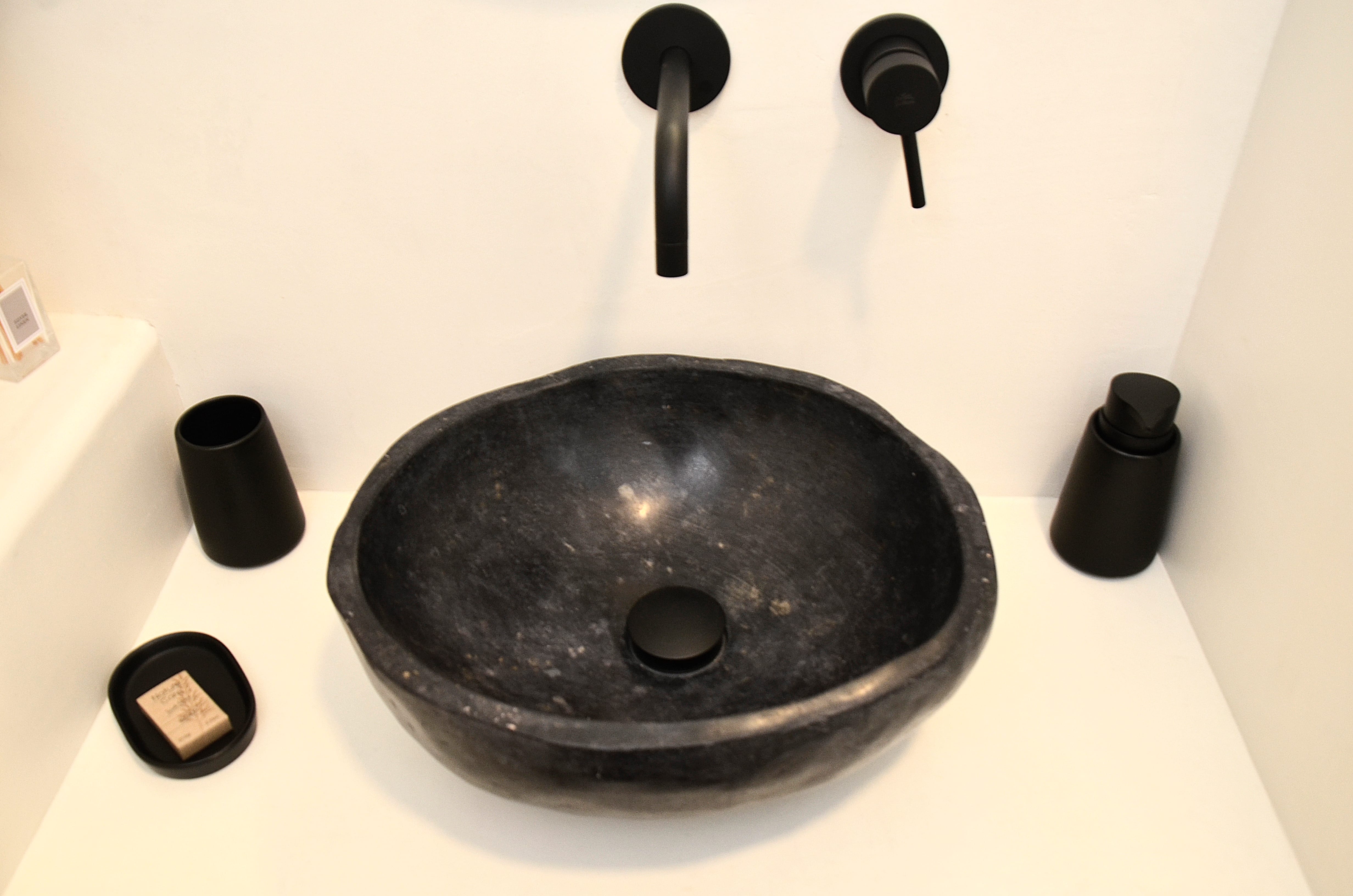 a black circular object with a black handle on a white surface