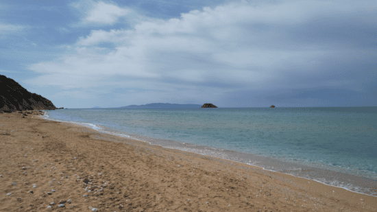 a sandy beach with a body of water in the background
