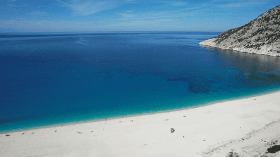 a body of water with a sandy beach and hills in the background