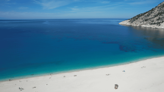 a body of water with a beach and mountains in the background