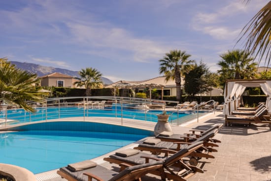 a swimming pool with a deck and palm trees and a building