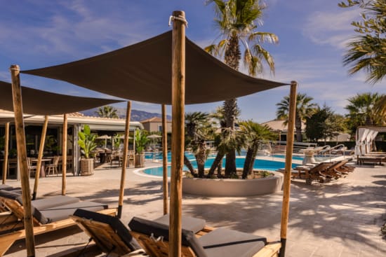 a pool with a lounge chair and umbrella on a beach