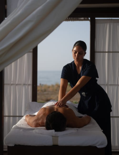 a woman standing over a man lying on a bed