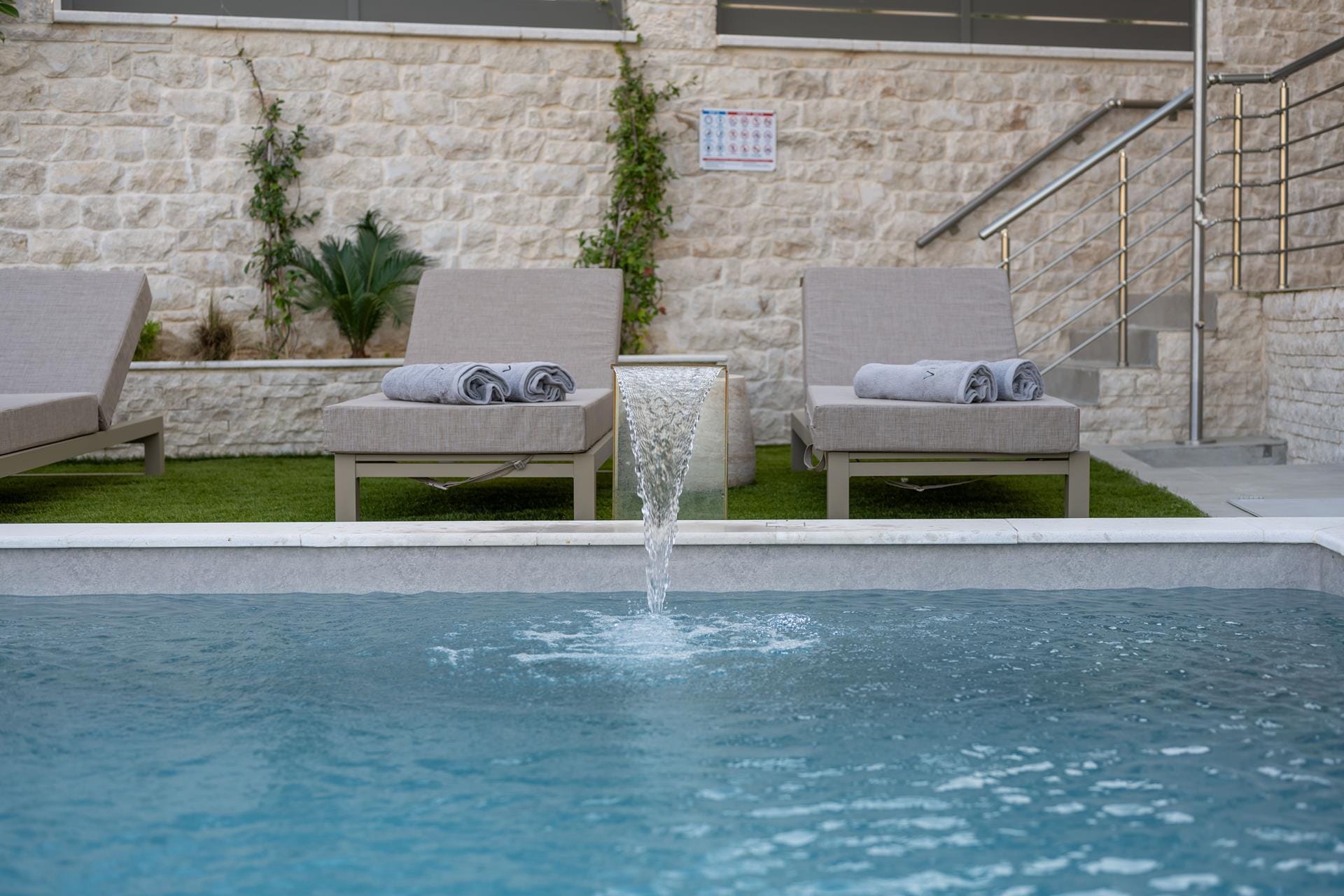 a pool with lounge chairs and a fountain