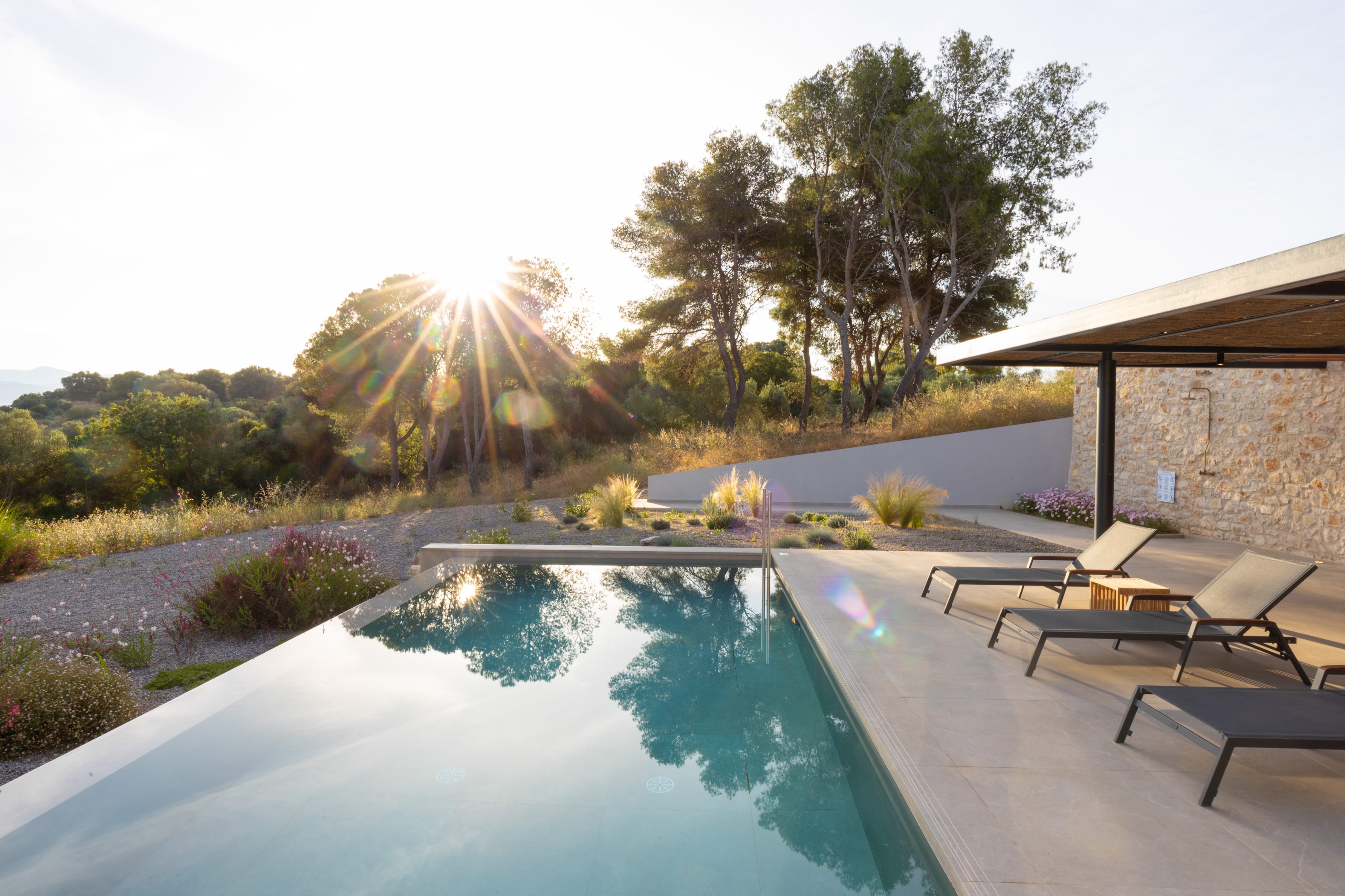 a pool with a deck and chairs by it and trees in the back