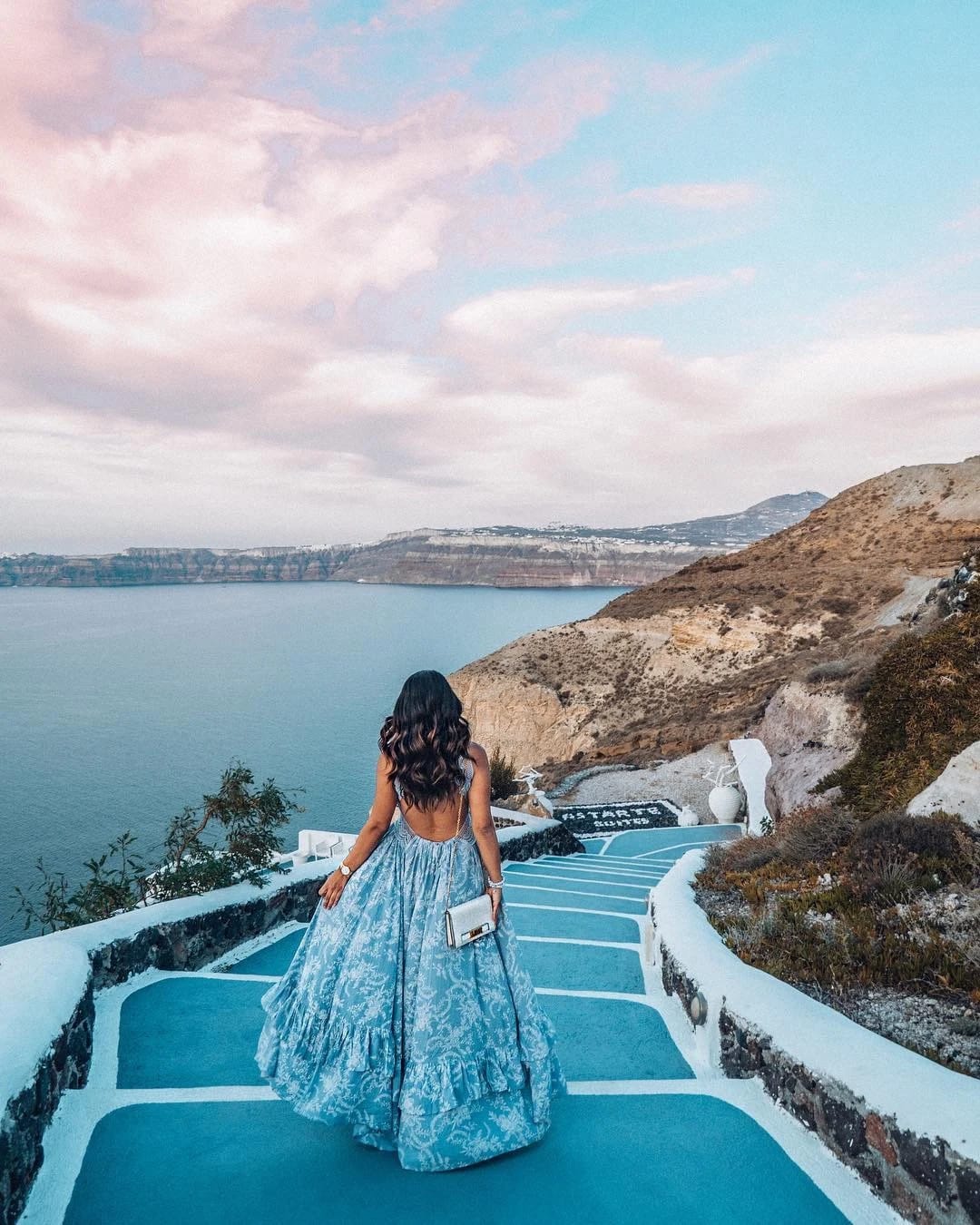 a person in a dress standing on a deck overlooking a body of water