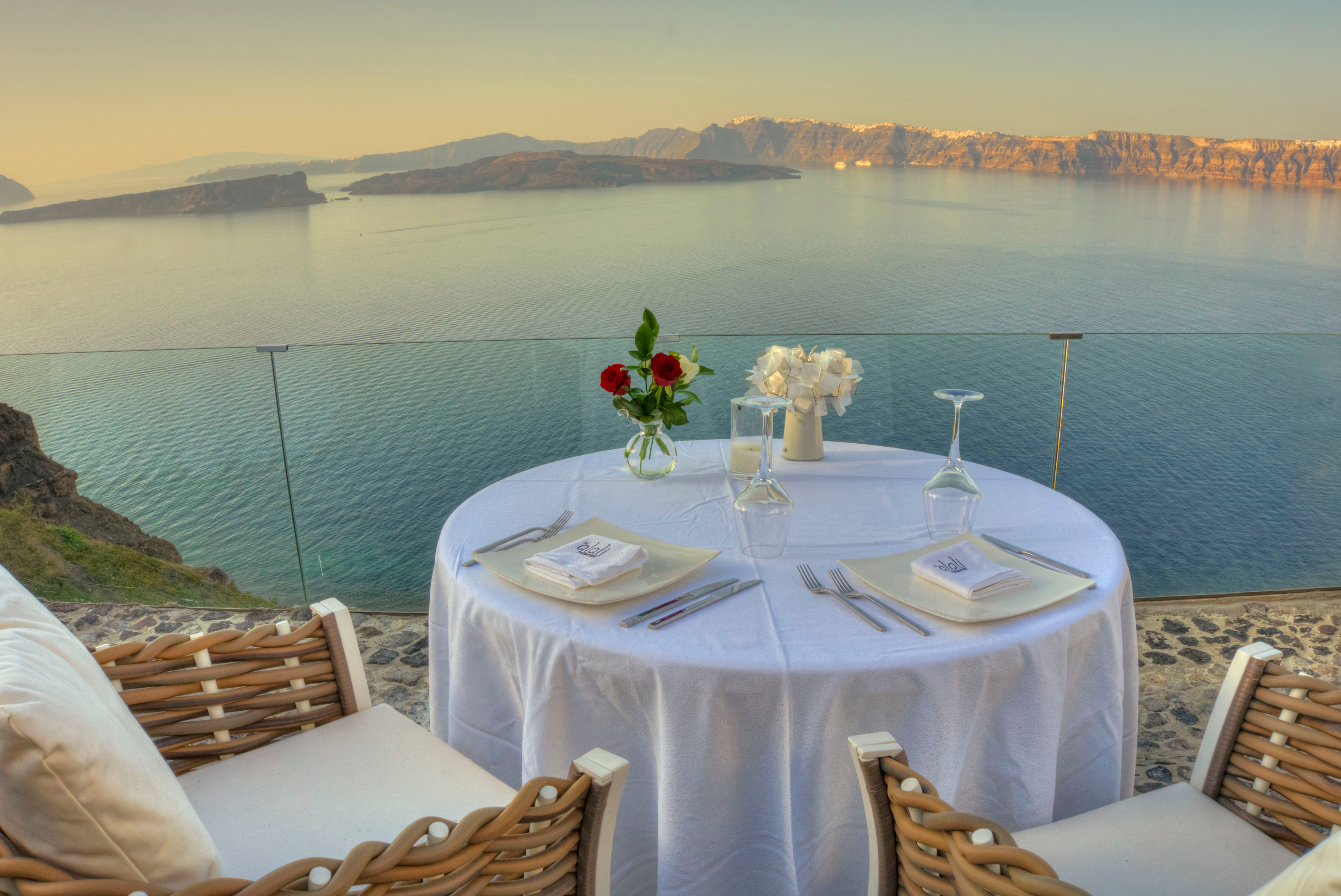 a table with a vase of flowers on it by a body of water