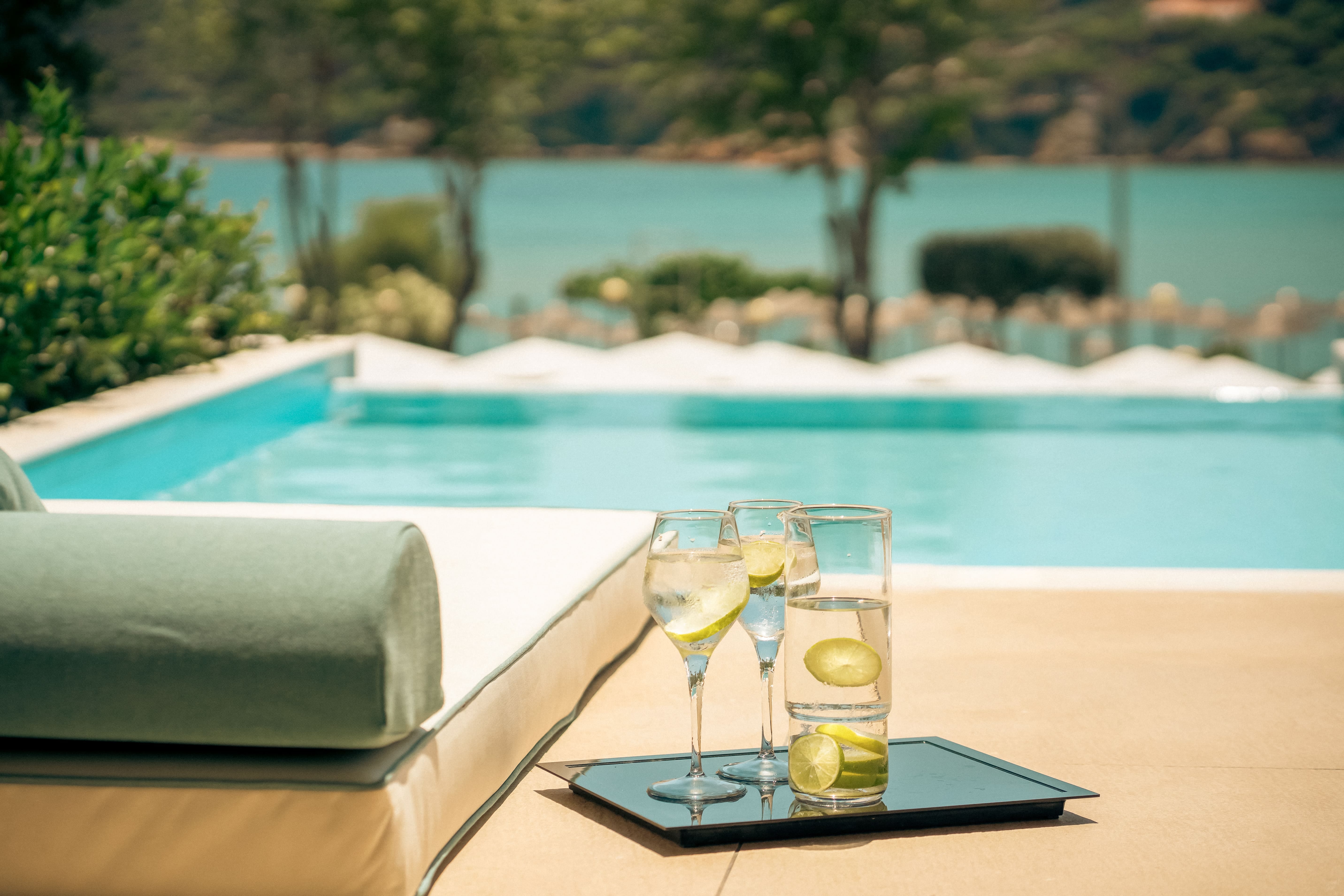 a tray of wine glasses with lime slices on it next to a pool