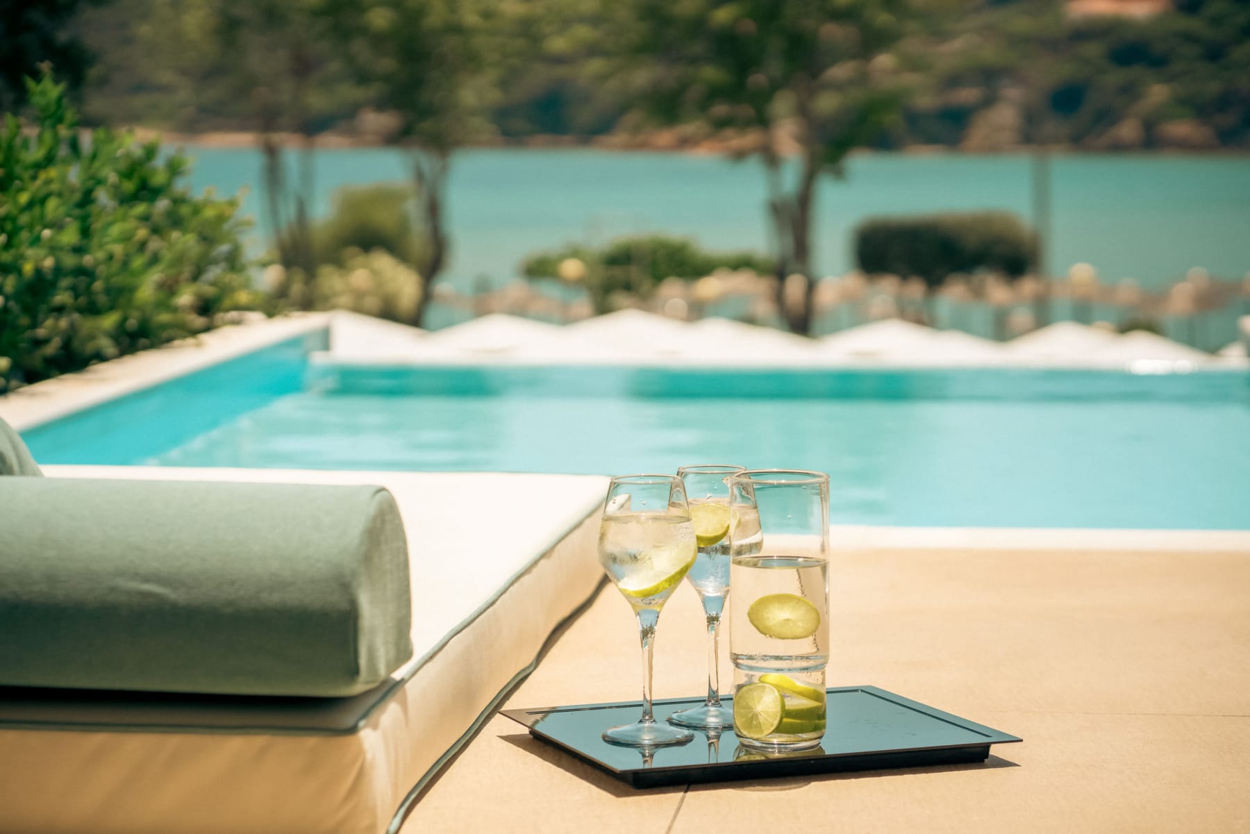 a tray of wine glasses with lime slices on it next to a pool