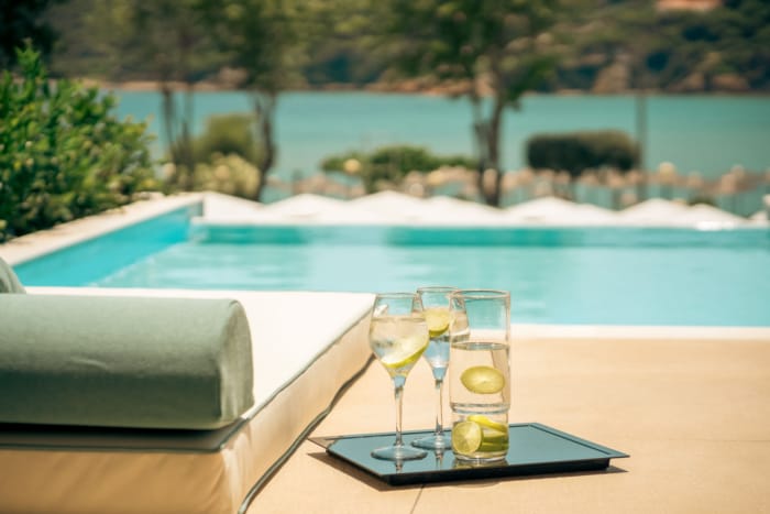 a tray of wine glasses with lime slices on it next to a pool