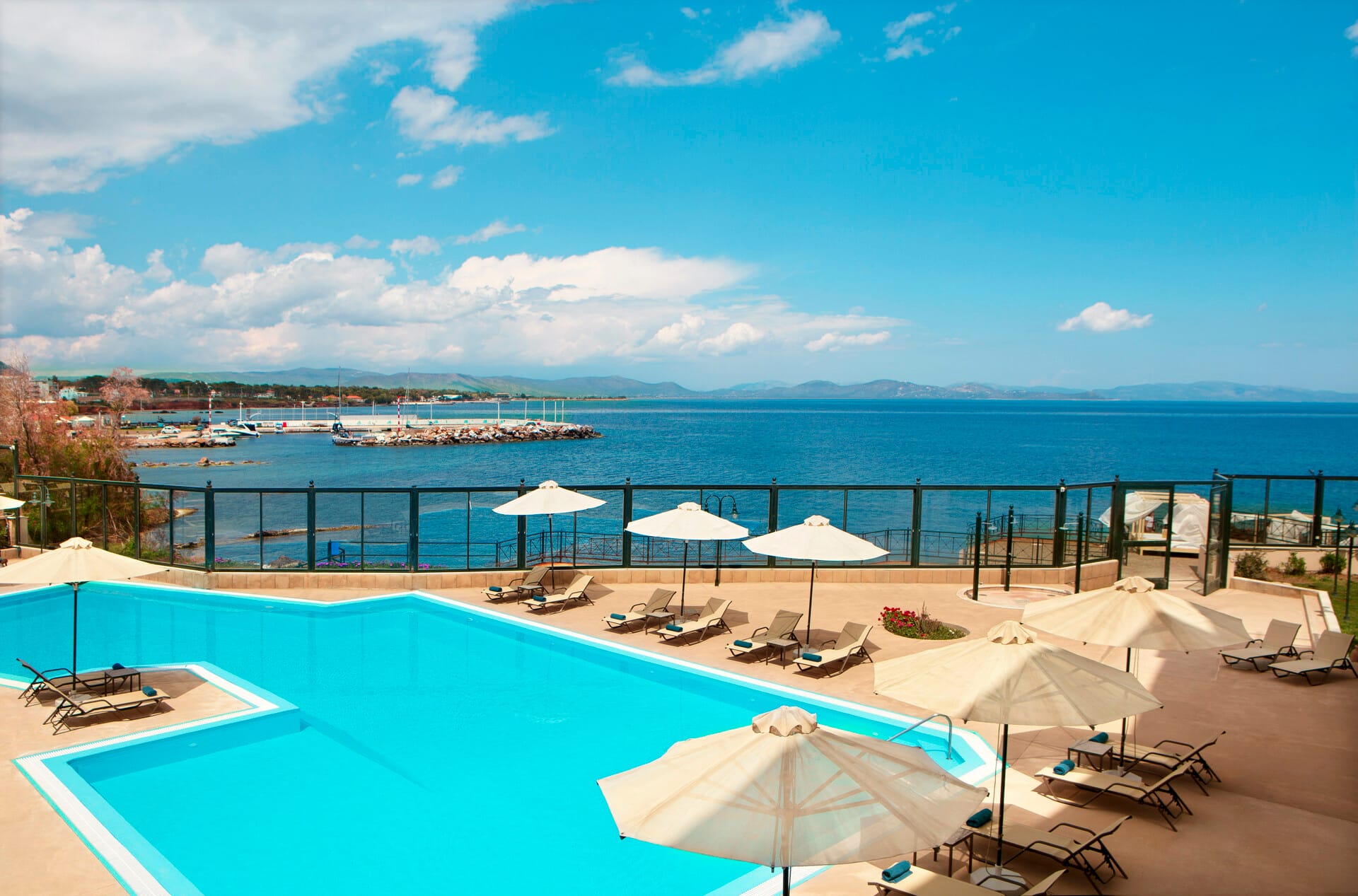 a pool with umbrellas and chairs by a beach